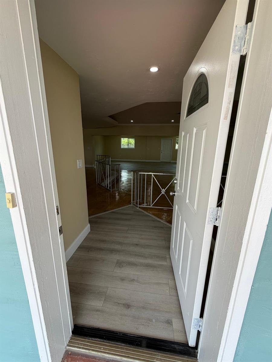 A view through an open front door into an entryway with wood-look flooring and railings — 1405 6th Street, West Palm Beach FL 33401, WEST PALM BEACH, FL