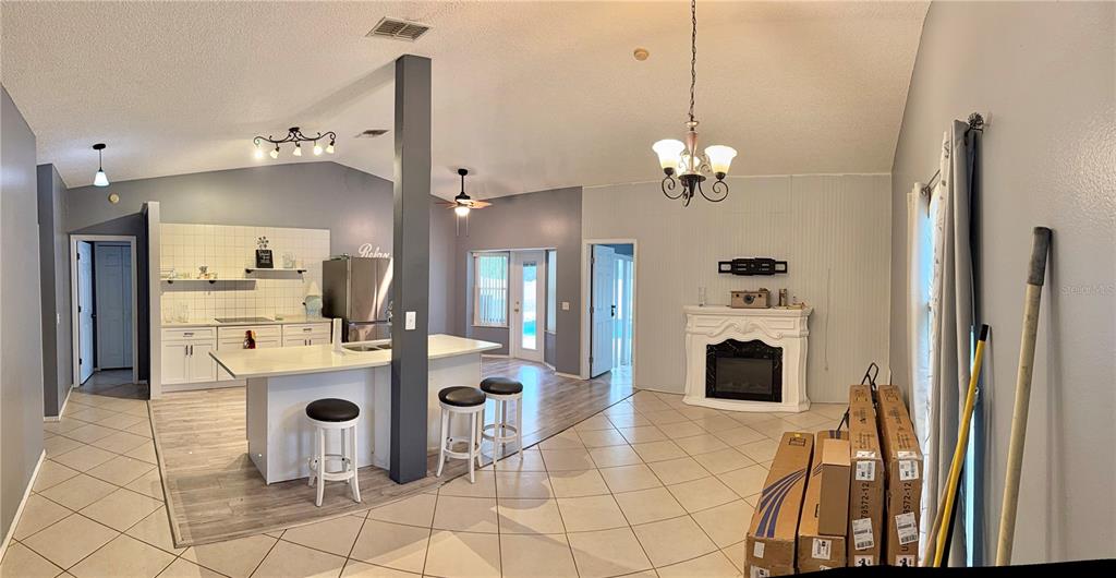 A kitchen with an island and a living area featuring a fireplace and tile flooring — 4811 PLINY COURT, KISSIMMEE, FL