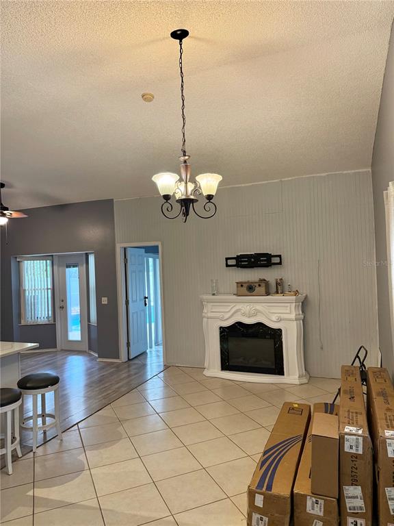 A room with tile flooring, a white fireplace, a chandelier, and boxes stacked on the floor — 4811 PLINY COURT, KISSIMMEE, FL