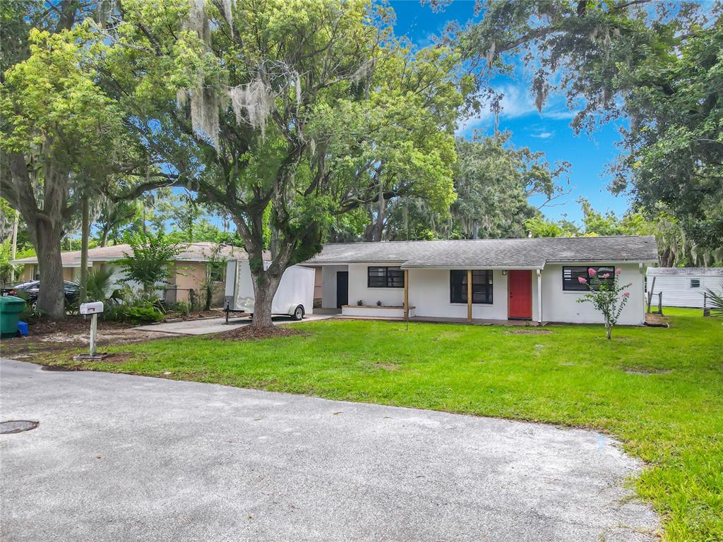 A single-story white house with a red front door sits on a grassy lot — 702 AVENUE A, DAYTONA BEACH, FL