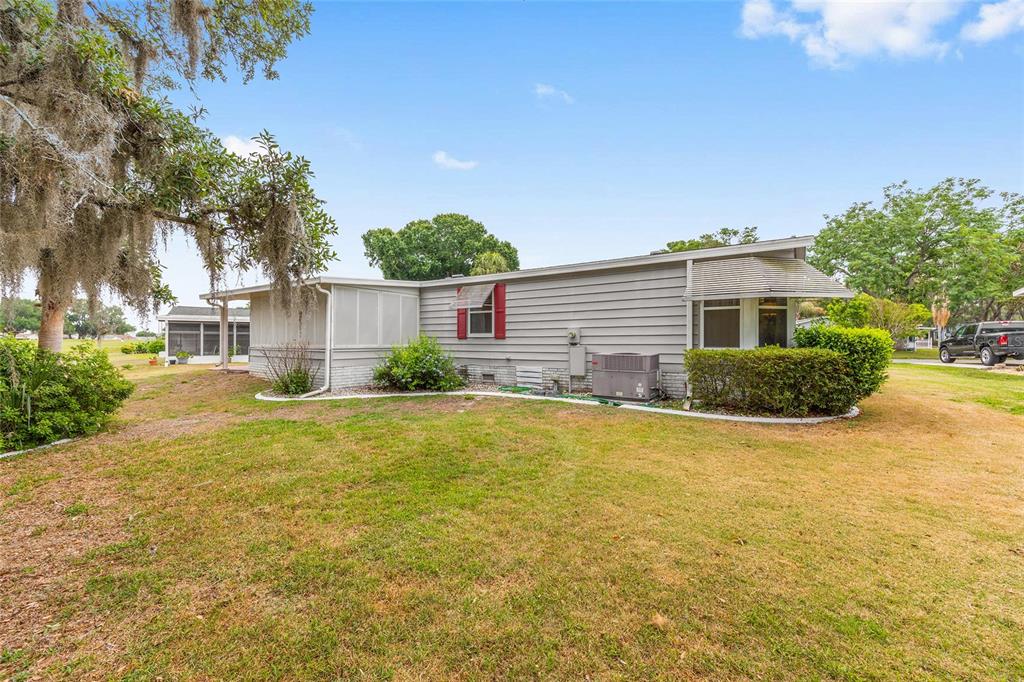 The exterior of a single-story house with gray horizontal siding and a large grassy yard — 951 OLEANDER STREET, LADY LAKE, FL