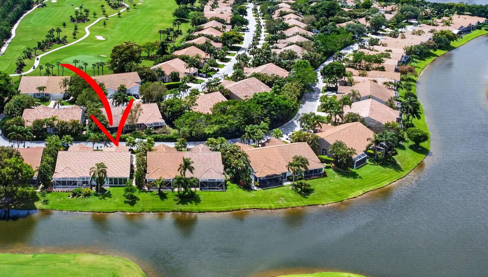 An aerial view of a residential neighborhood featuring houses with tile roofs along a lake — 4634 Carlton Golf Drive, Lake Worth FL 33449, LAKE WORTH, FL