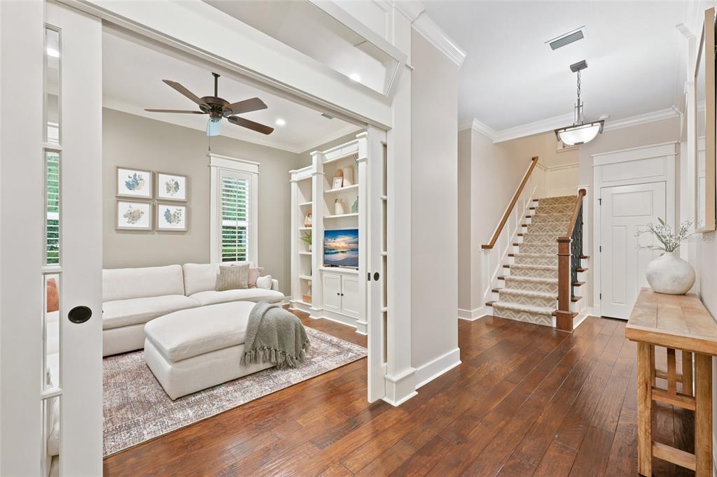 A living room with a white sofa and built-in shelves sits beside a wooden staircase — 774 SW 134TH WAY, NEWBERRY, FL
