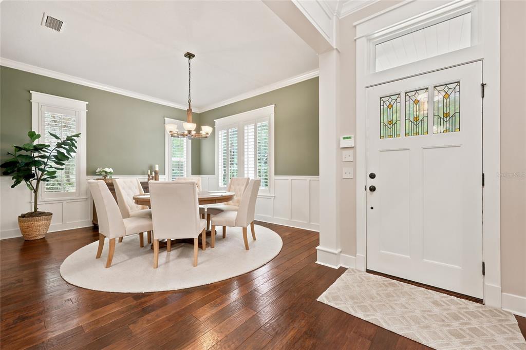 A dining room with sage green walls, white wainscoting, and a white front door — 774 SW 134TH WAY, NEWBERRY, FL