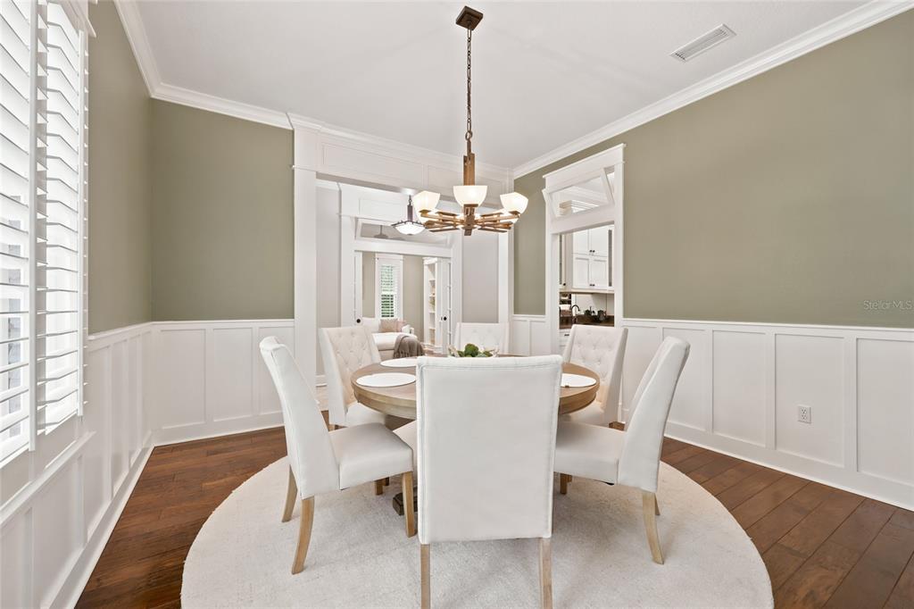 A dining room features white wainscoting, a round table with four chairs, and a chandelier — 774 SW 134TH WAY, NEWBERRY, FL