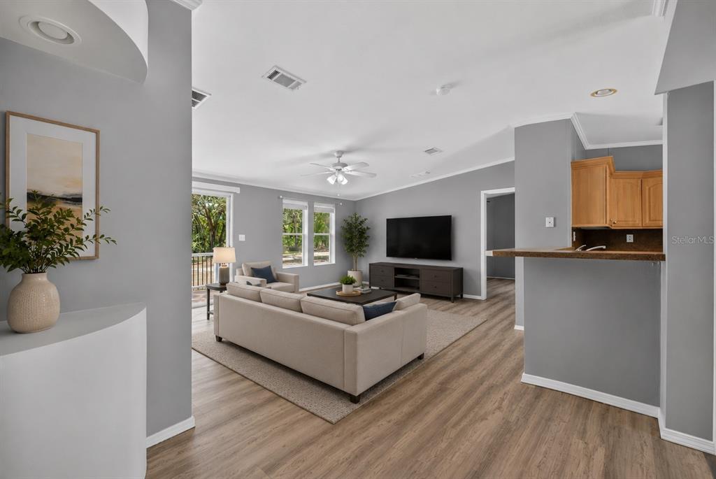 A living room with light gray walls, wood-look flooring, a beige sofa, and a television — 357 WALTER PLACE, FRUITLAND PARK, FL