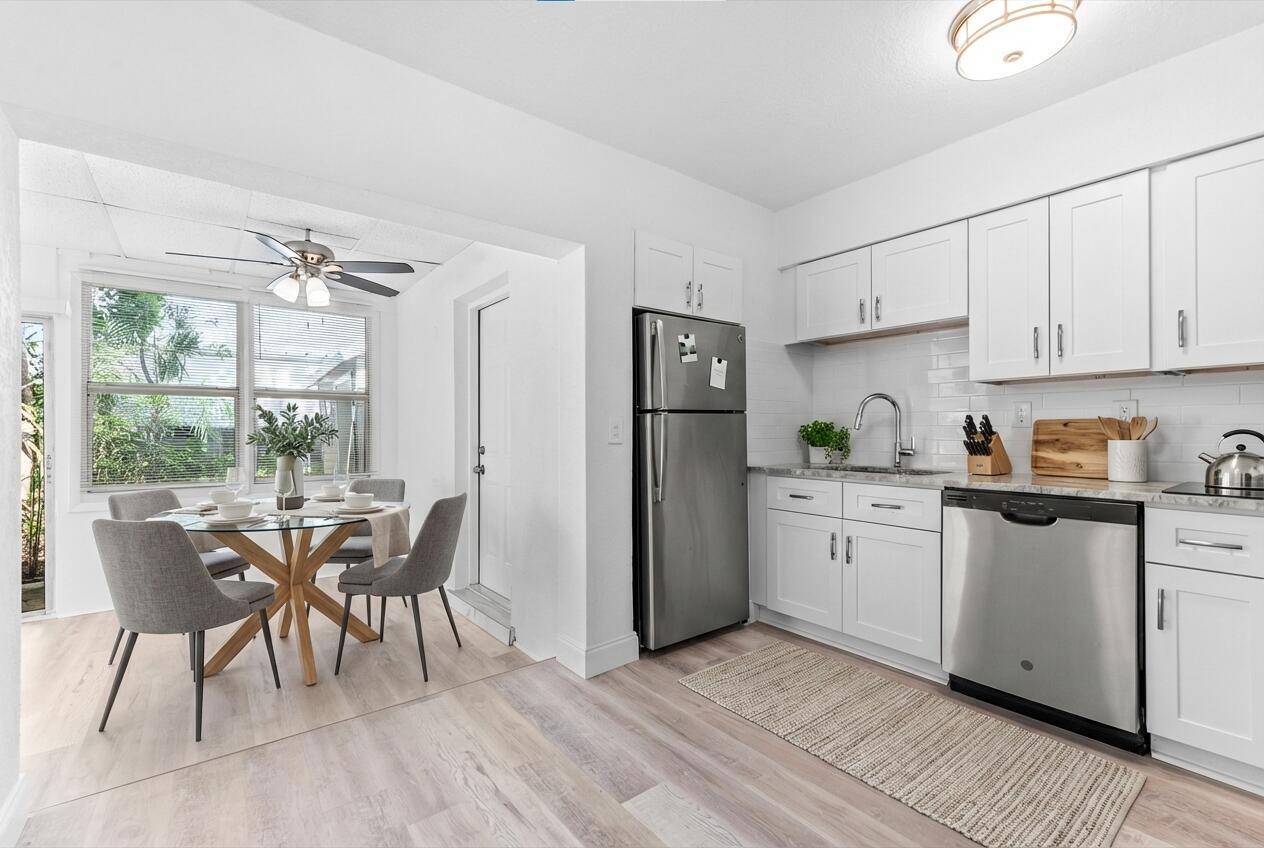 A kitchen with white cabinets and stainless steel appliances opens to a dining area — 308 Stillwater Drive, Jupiter FL 33458, JUPITER, FL
