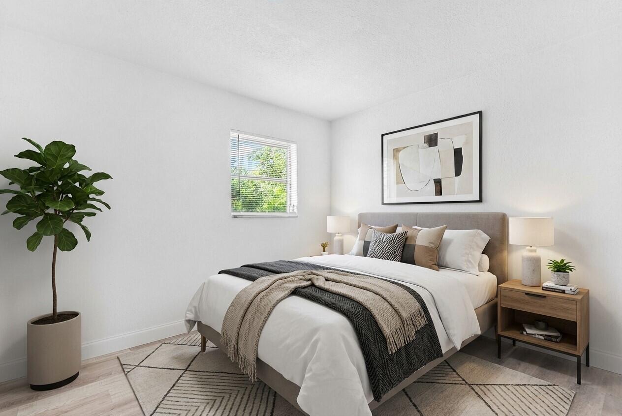 A bedroom with a bed, nightstand, potted plant, and window in a neutral-toned room — 308 Stillwater Drive, Jupiter FL 33458, JUPITER, FL