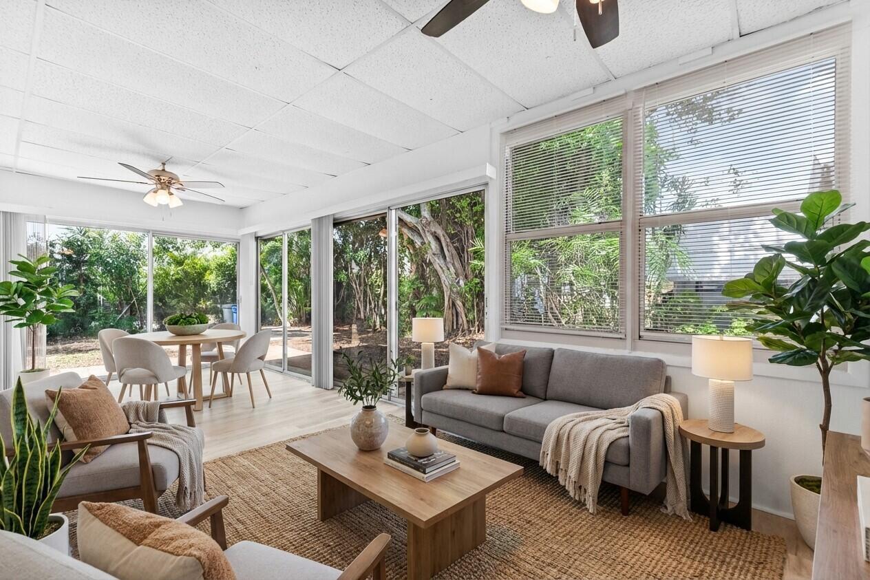 A sunroom features a gray sofa, wood coffee table, dining area, and large glass windows — 308 Stillwater Drive, Jupiter FL 33458, JUPITER, FL