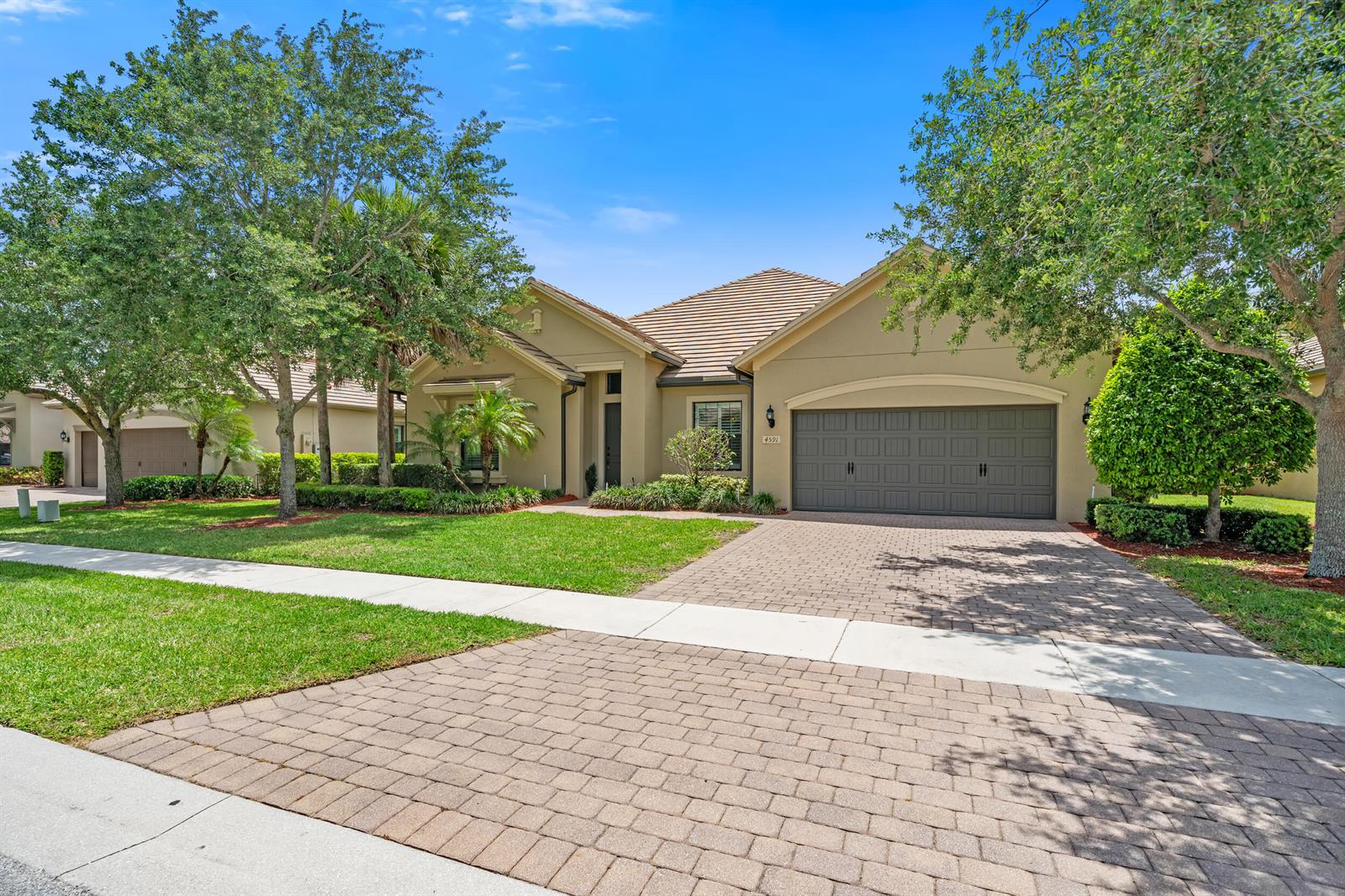 A single-story house with a tan exterior, a paver driveway, and a two-car garage — 4591 Siena Circle, Wellington FL 33414, WELLINGTON, FL