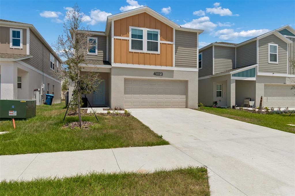 A two-story suburban house with a tan stucco facade, brown siding, and a two-car garage — 4023 GARDENIA AVE, HAINES CITY, FL