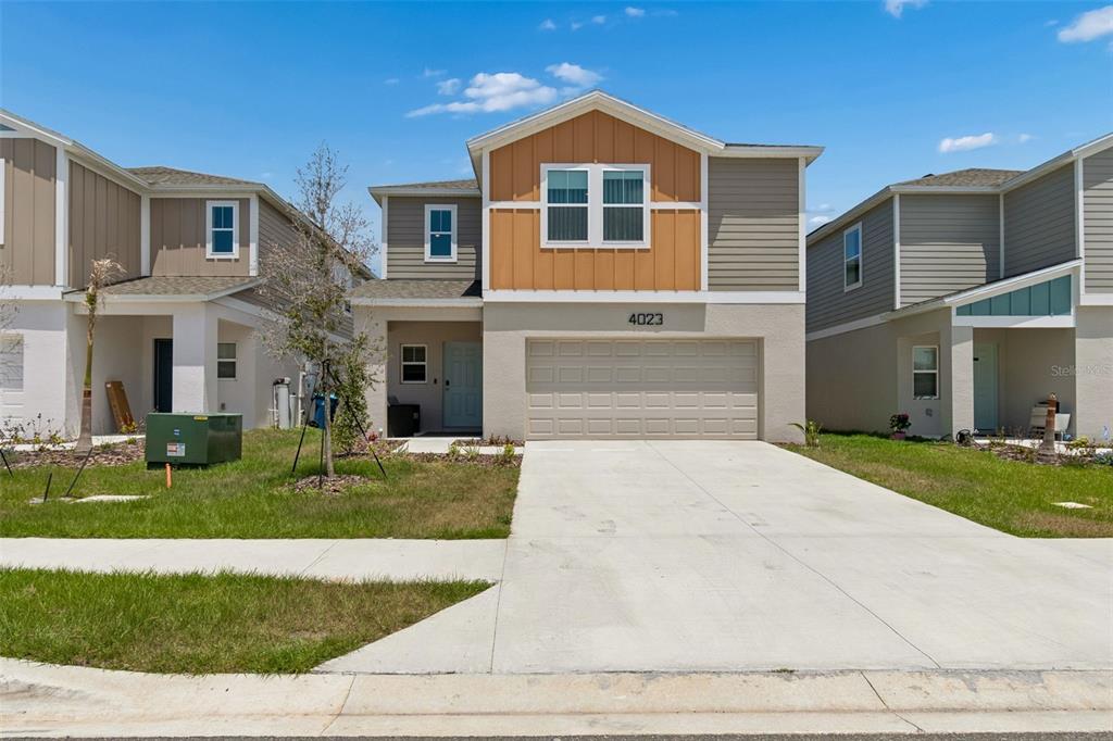 A two-story suburban house with a beige stucco exterior, a garage, and a driveway — 4023 GARDENIA AVE, HAINES CITY, FL