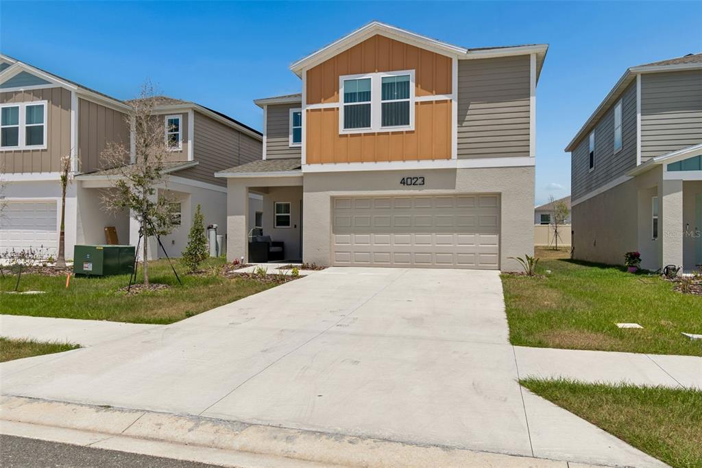 A two-story suburban house features a tan garage, vertical orange siding, and a concrete driveway — 4023 GARDENIA AVE, HAINES CITY, FL