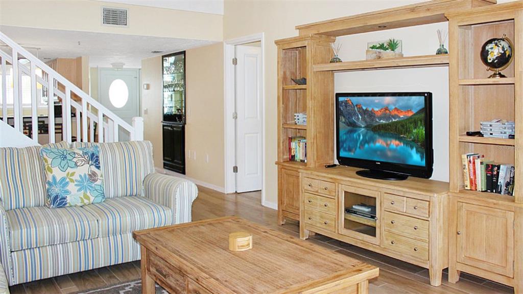 A living room features a striped sofa, wooden coffee table, and a large media entertainment center — 1305 SIESTA BAYSIDE DRIVE UNIT 1305-B, SARASOTA, FL