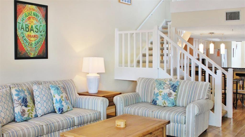 A living room features two striped sofas, a wooden coffee table, and a Tabasco poster — 1305 SIESTA BAYSIDE DRIVE UNIT 1305-B, SARASOTA, FL