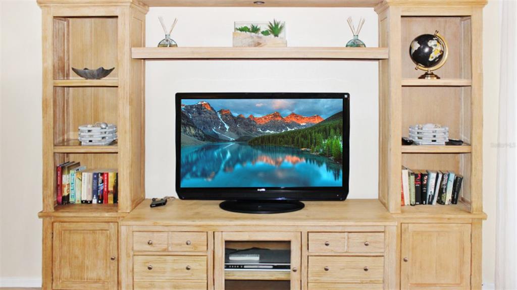A light wood entertainment center features open shelving, storage cabinets, and a television — 1305 SIESTA BAYSIDE DRIVE UNIT 1305-B, SARASOTA, FL