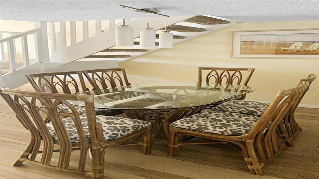 A dining area features a glass-topped rattan table with patterned chairs beneath a modern light — 1305 SIESTA BAYSIDE DRIVE UNIT 1305-B, SARASOTA, FL