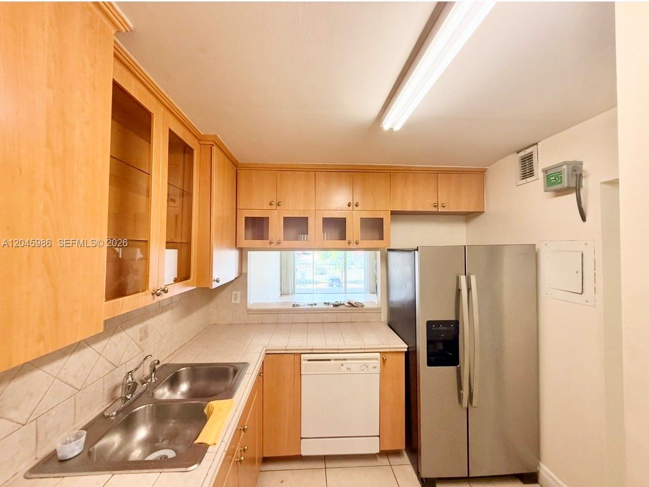 A kitchen features light wood cabinets, a stainless steel refrigerator, and a double basin sink — 1975 W 44th Pl # 203, Hialeah FL 33012, HIALEAH, FL