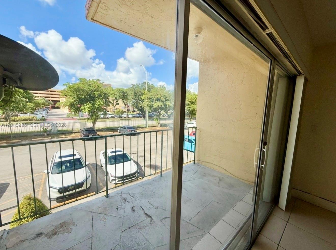 A balcony with a metal railing overlooks a parking lot and trees — 1975 W 44th Pl # 203, Hialeah FL 33012, HIALEAH, FL