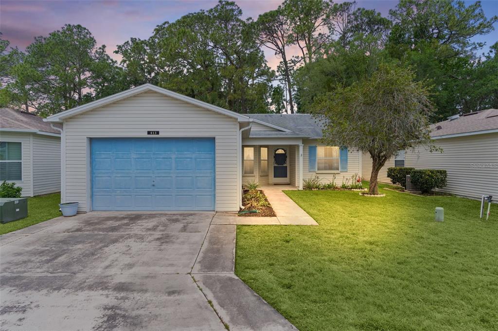 A single-story house with beige siding, a blue garage door, and a front lawn — 413 WESTWOOD DRIVE, LEESBURG, FL