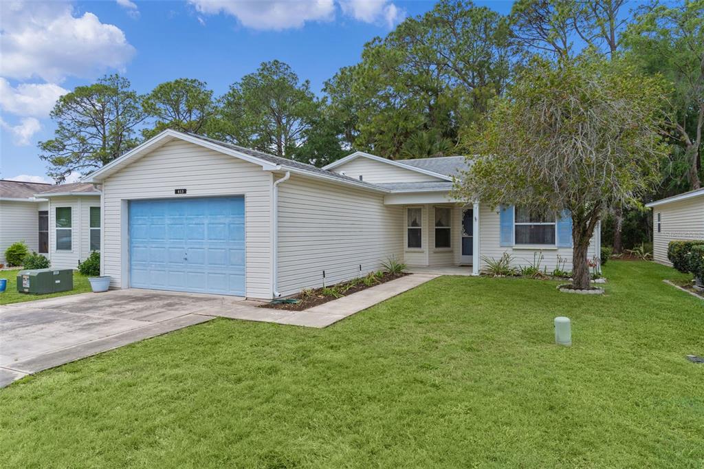 A single-story house with light siding, a blue garage door, and a front lawn — 413 WESTWOOD DRIVE, LEESBURG, FL