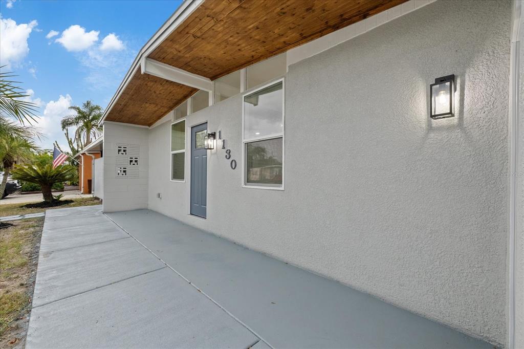 A gray house exterior features a blue front door, a wood-paneled porch ceiling, and sconces — 1130 DOGWOOD AVENUE, TAMPA, FL