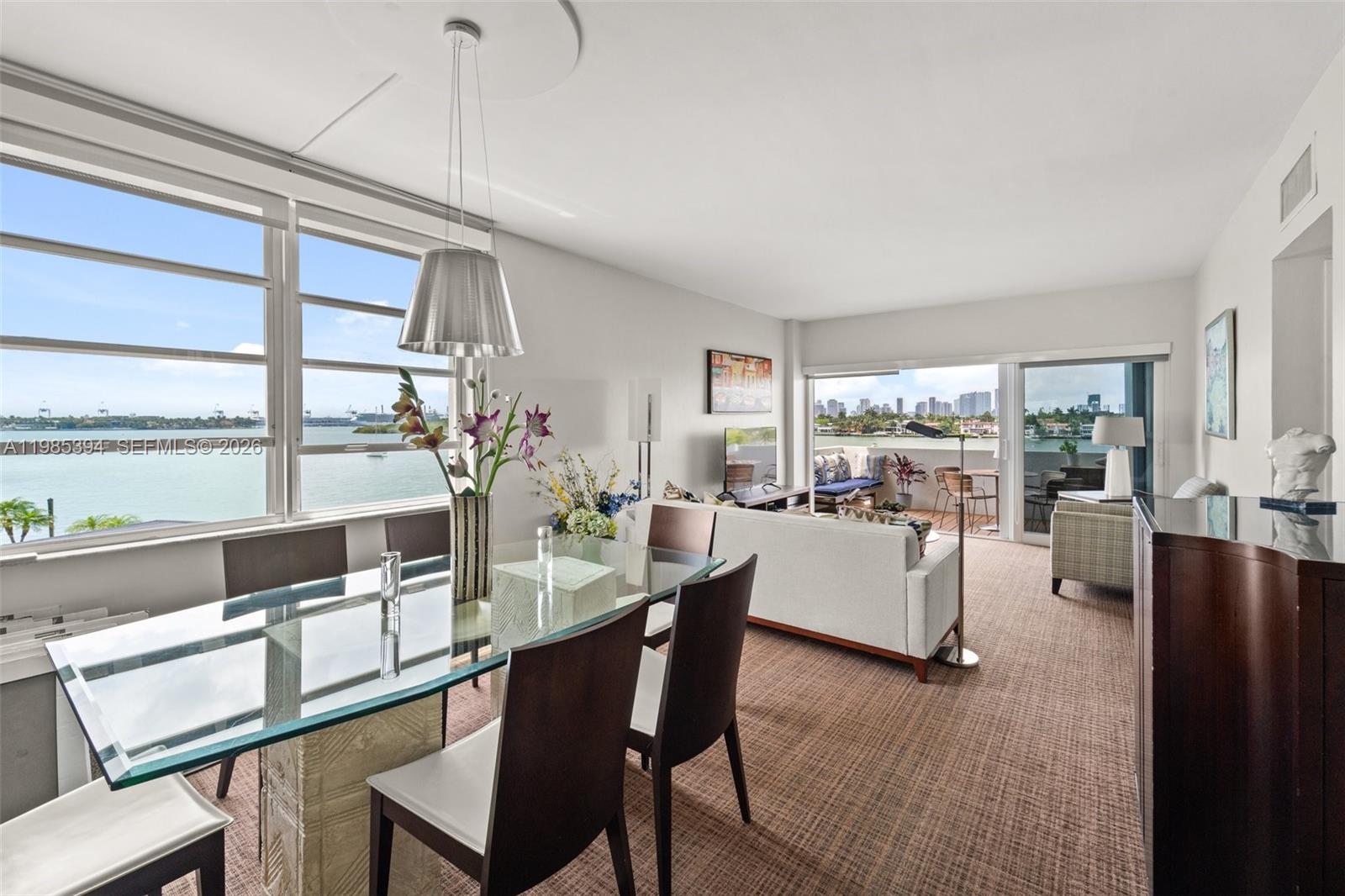 A dining and living area features a glass table, carpeted floors, and a balcony view — 3 Island Ave # 04I, Miami Beach FL 33139, MIAMI BEACH, FL