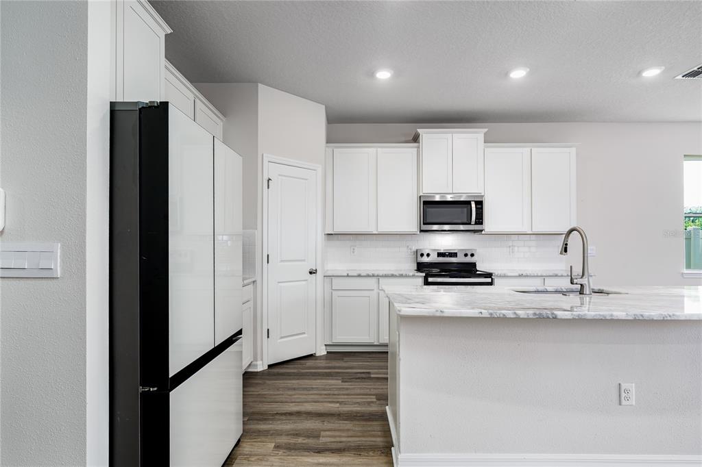 A kitchen features white cabinets, stainless steel appliances, and a marble-patterned island countertop — 10622 EUSTIS DRIVE, PARRISH, FL
