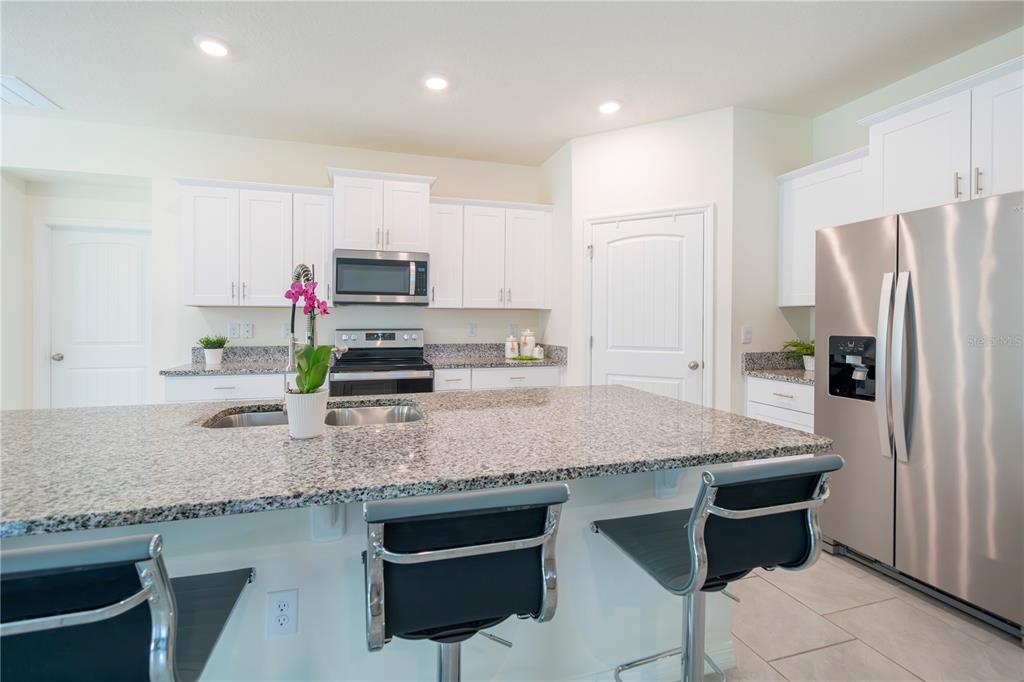 A kitchen features white cabinets, granite countertops, stainless steel appliances, and a central island — 1624 BARBERRY DRIVE, KISSIMMEE, FL