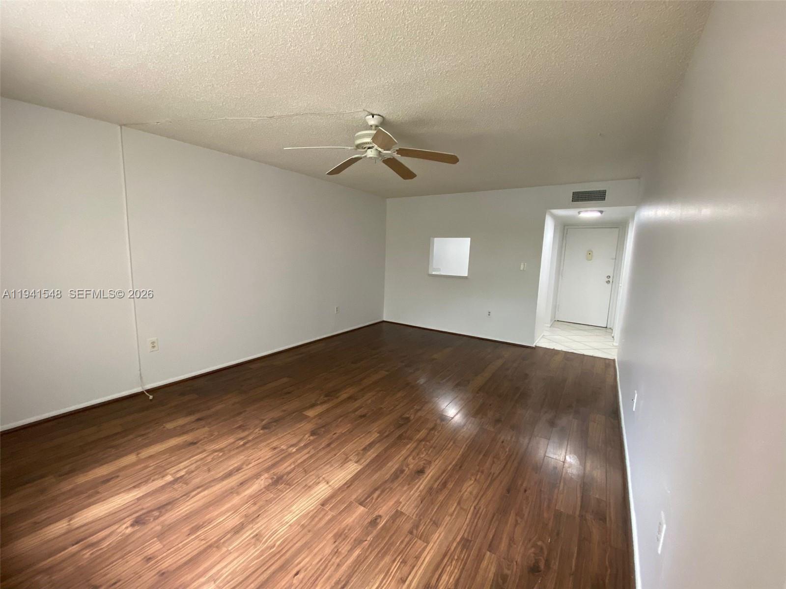 An empty room features dark wood-look flooring, white walls, and a ceiling fan — 4344 NW 9th Ave # 3D, Deerfield Beach FL 33064, DEERFIELD BEACH, FL