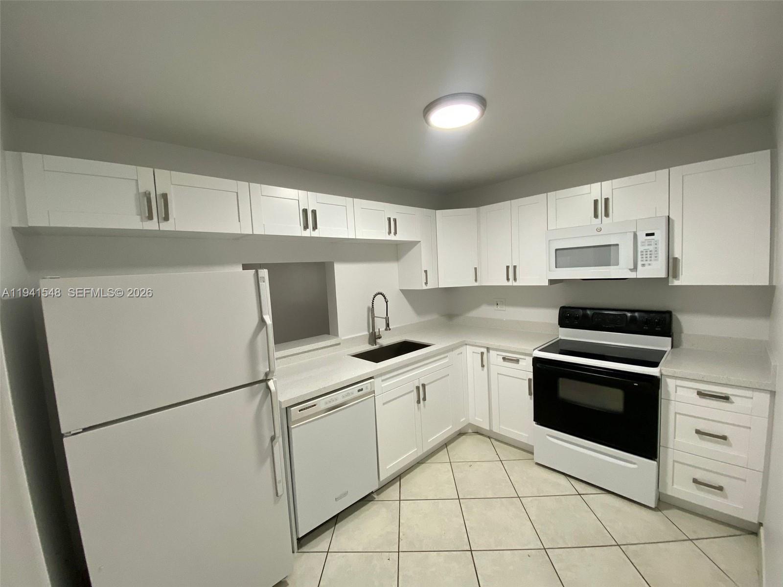 A kitchen features white cabinets, white appliances, a dark sink, and light-colored tile flooring — 4344 NW 9th Ave # 3D, Deerfield Beach FL 33064, DEERFIELD BEACH, FL