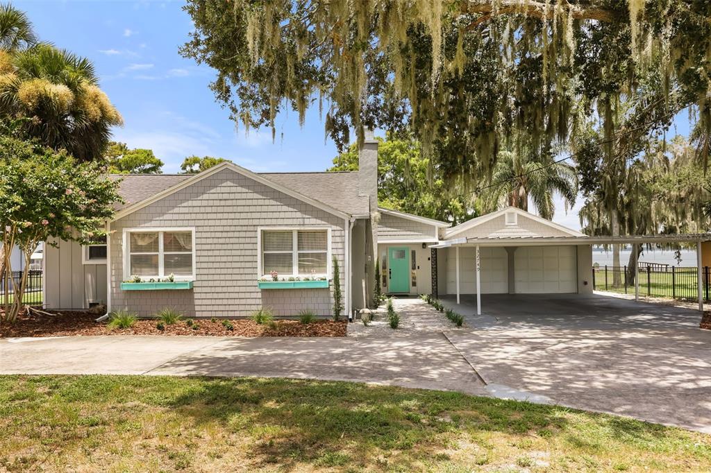 A single-story house with gray shingles, a turquoise front door, and an attached carport — 32749 LAKE EUSTIS DRIVE, TAVARES, FL