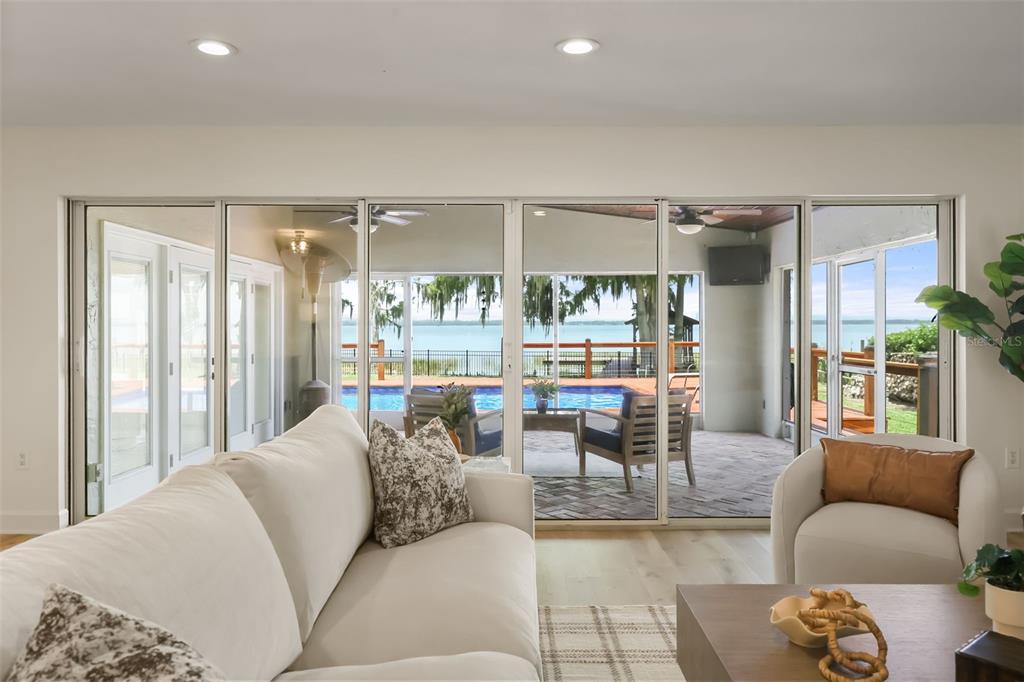 A living room with a white sofa faces large sliding glass doors overlooking a pool — 32749 LAKE EUSTIS DRIVE, TAVARES, FL