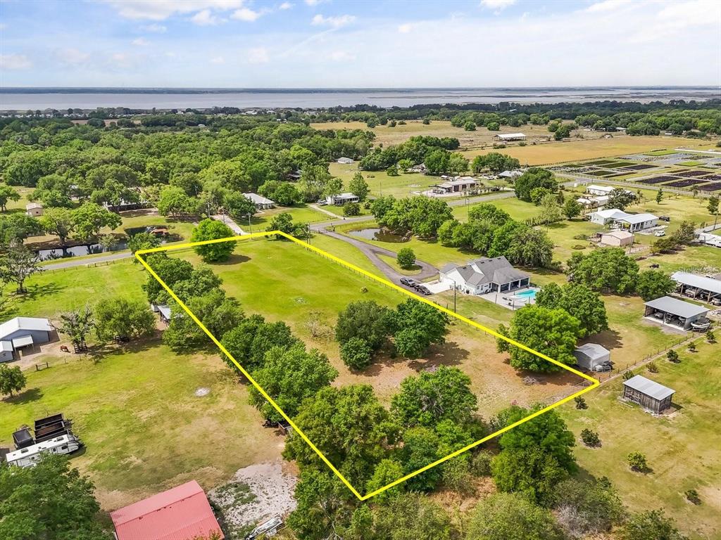 An aerial view shows a large, rectangular grassy lot outlined in yellow near rural houses — 3265 BARBER ROAD, ST CLOUD, FL