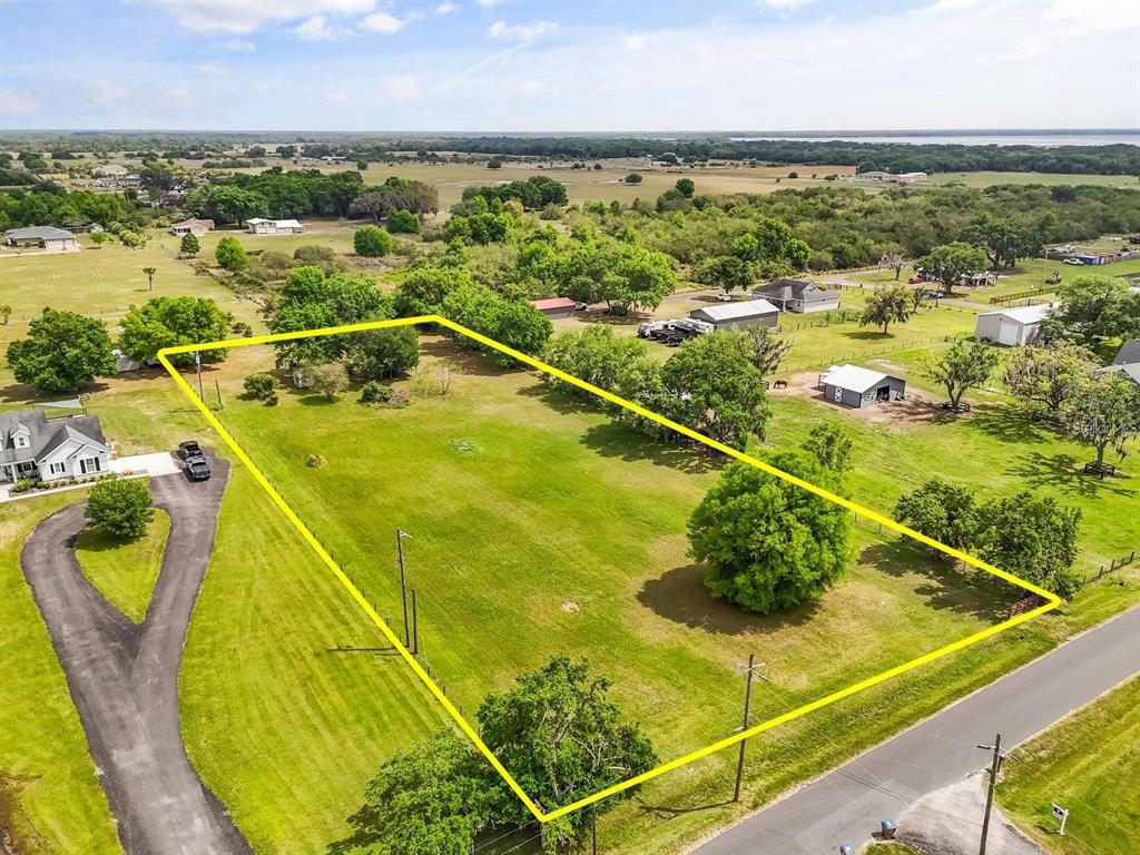 An aerial view shows a large, rectangular grassy lot outlined in yellow near a road — 3265 BARBER ROAD, ST CLOUD, FL