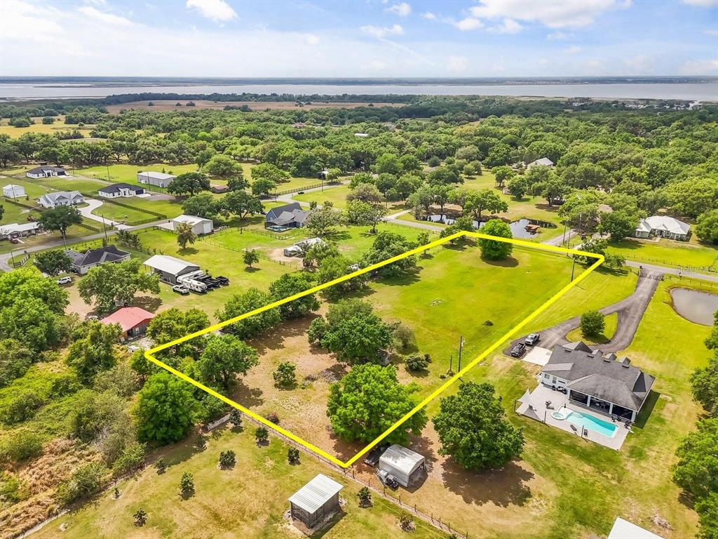An aerial view shows a large, rectangular grassy lot outlined in yellow near a house — 3265 BARBER ROAD, ST CLOUD, FL