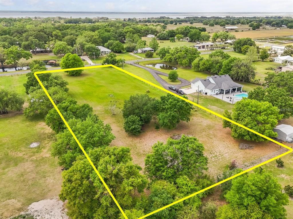 An aerial view shows a large, rectangular grassy lot outlined in yellow near a house — 3265 BARBER ROAD, ST CLOUD, FL