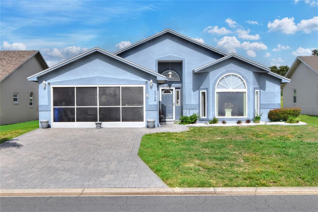 A blue single-story house features a paved driveway, a screened garage, and a large window — 6068 SWALLOW DRIVE, LAKELAND, FL