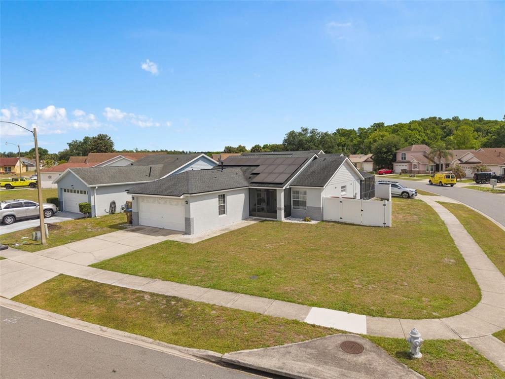 An exterior view of a single-story suburban house with solar panels on the roof — 101 SENECA POINT TRL, KISSIMMEE, FL