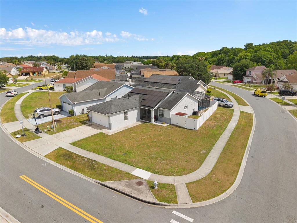 An aerial view shows a suburban house with solar panels on a corner lot — 101 SENECA POINT TRL, KISSIMMEE, FL