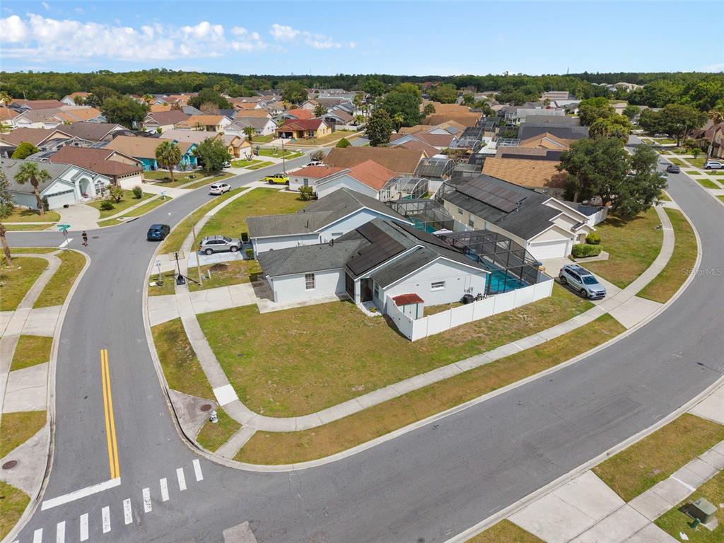 An aerial view shows a suburban house with a pool enclosure and solar panels — 101 SENECA POINT TRL, KISSIMMEE, FL