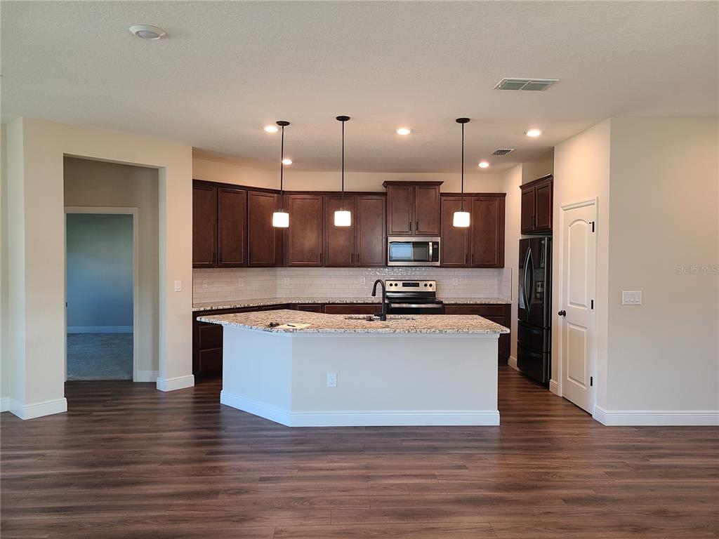 A kitchen features dark wood cabinets, granite countertops, stainless steel appliances, and pendant lighting — 5736 143RD COURT E, BRADENTON, FL