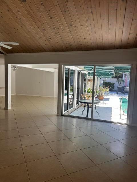 A room with tile floors and a wood-paneled ceiling overlooks a pool patio — 112 E Coral Fish Lane, Jupiter FL 33477, JUPITER, FL