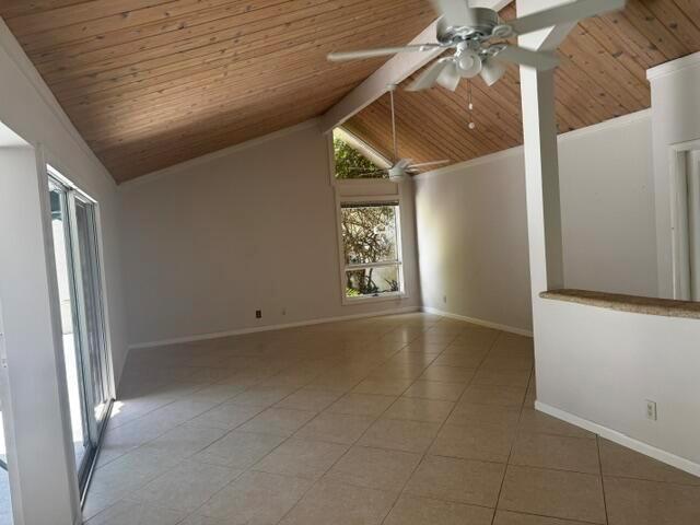 An empty room features a vaulted wood-paneled ceiling, tile flooring, and a large window — 112 E Coral Fish Lane, Jupiter FL 33477, JUPITER, FL