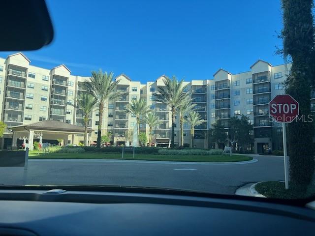 A view from a vehicle shows a multi-story apartment building with palm trees and a fountain — 14501 GROVE RESORT AVENUE UNIT 2129, WINTER GARDEN, FL