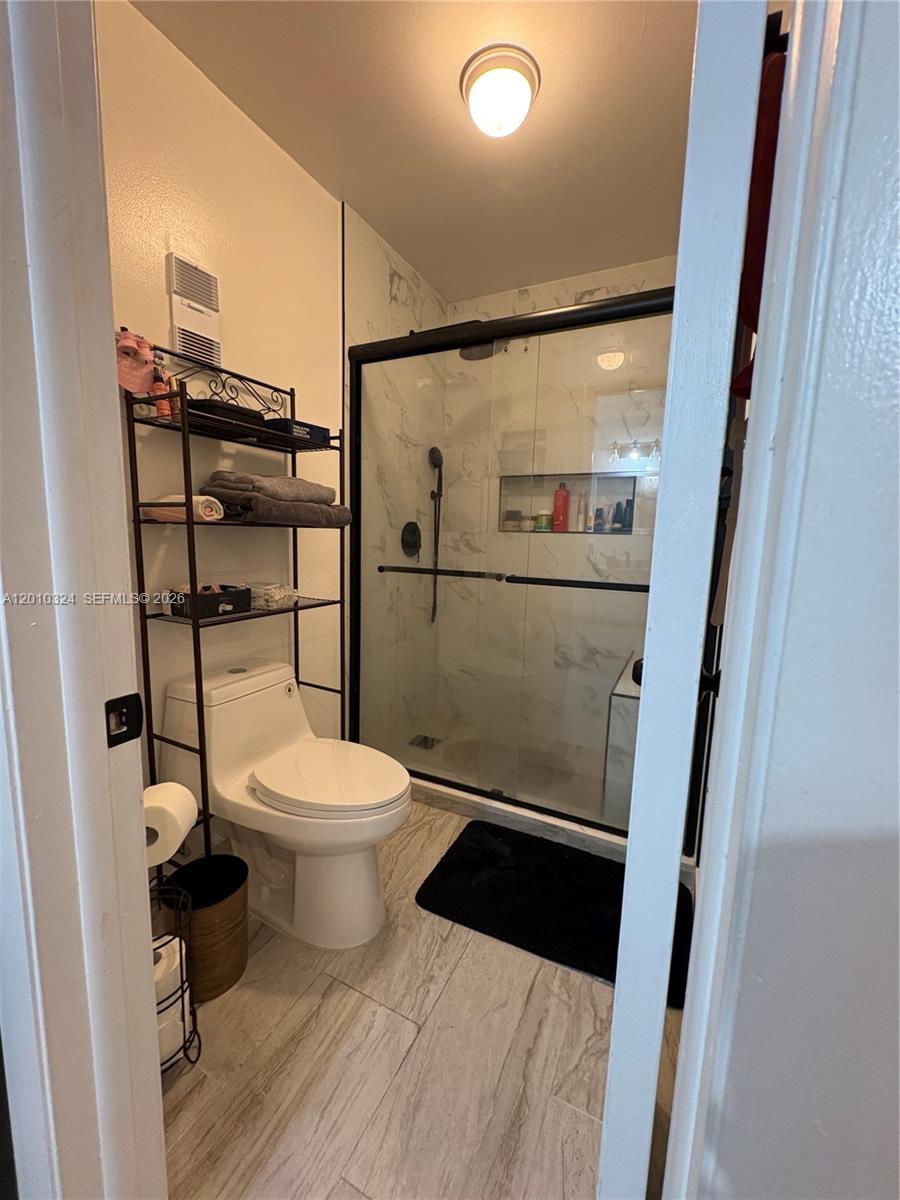A bathroom features a white toilet, a metal storage rack, and a glass-enclosed walk-in shower — 5424 Gate Lake Rd # 5424, Tamarac FL 33319, TAMARAC, FL