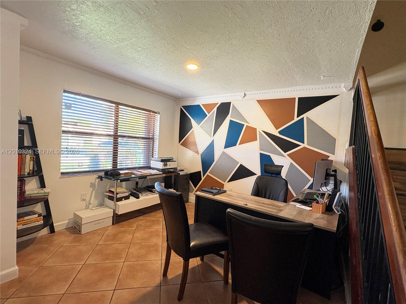 A home office features a geometric accent wall, a desk with two chairs, and tile flooring — 5424 Gate Lake Rd # 5424, Tamarac FL 33319, TAMARAC, FL