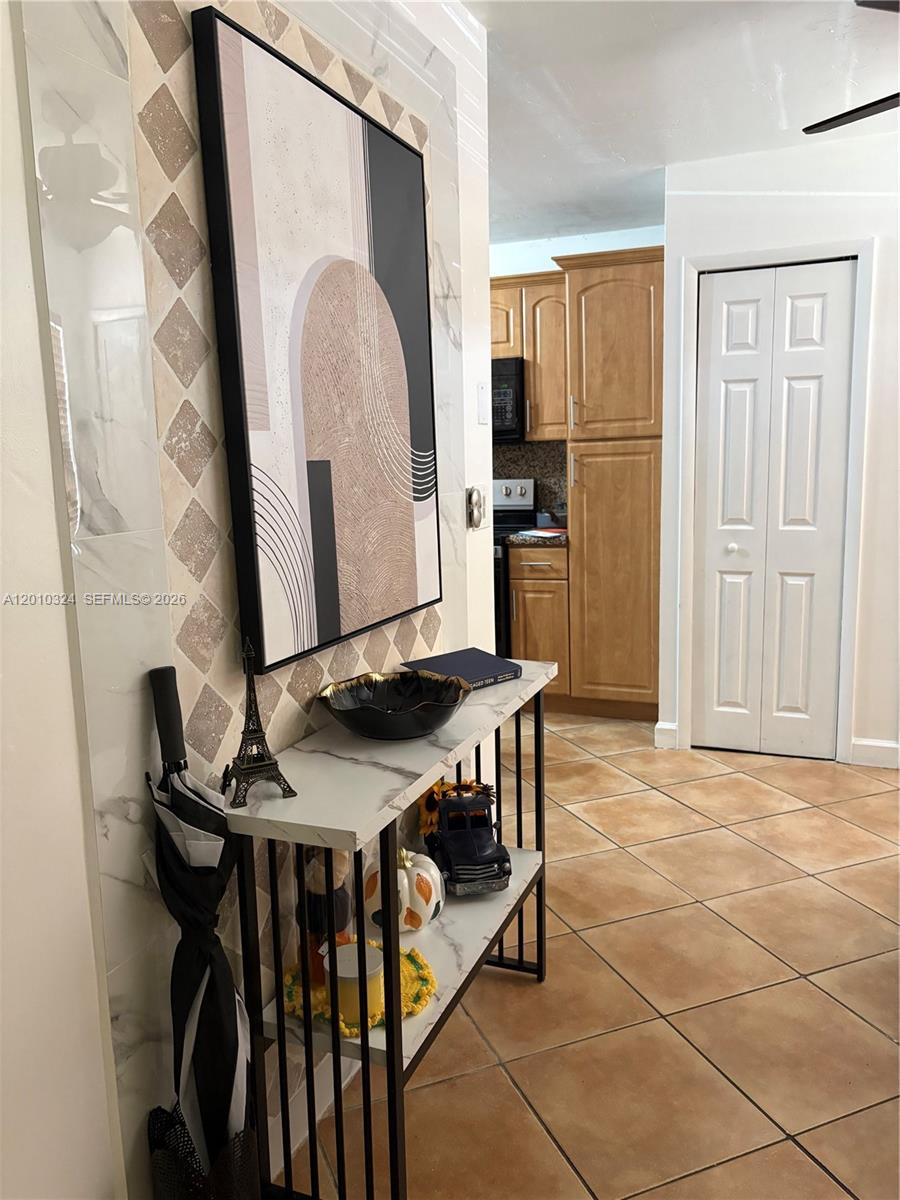 A console table with decor sits in a hallway featuring tiled floors and wall art — 5424 Gate Lake Rd # 5424, Tamarac FL 33319, TAMARAC, FL