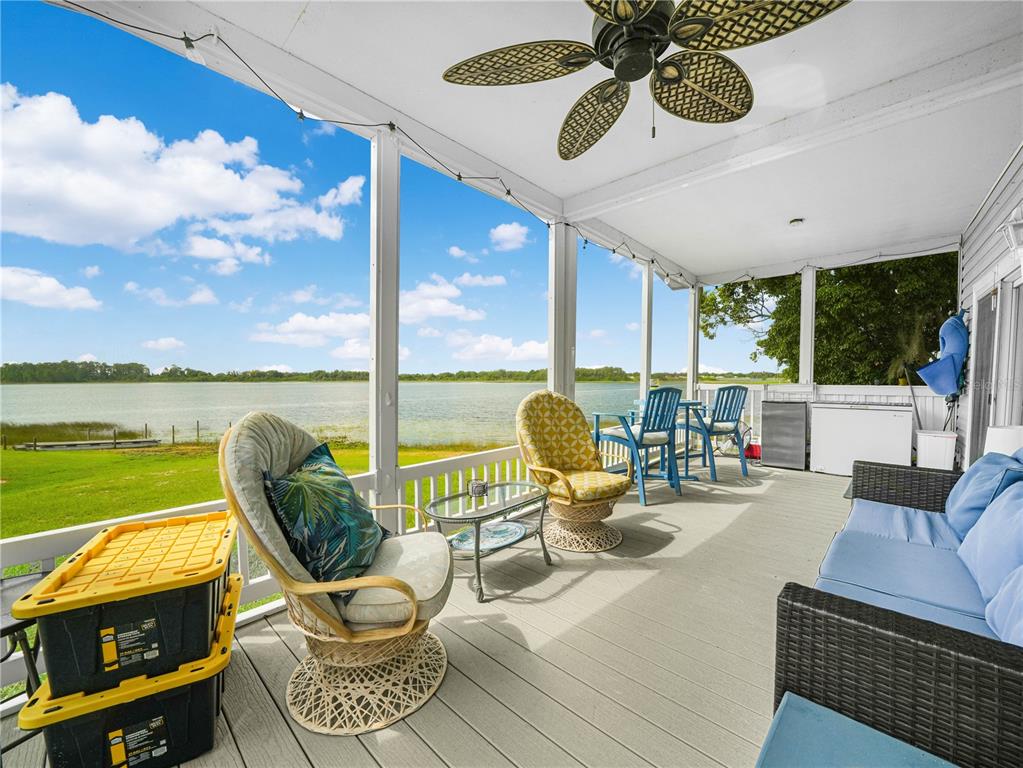 A screened-in porch with wicker furniture and a ceiling fan overlooks a lake — 29 WOODRUFF WAY, LAKE WALES, FL