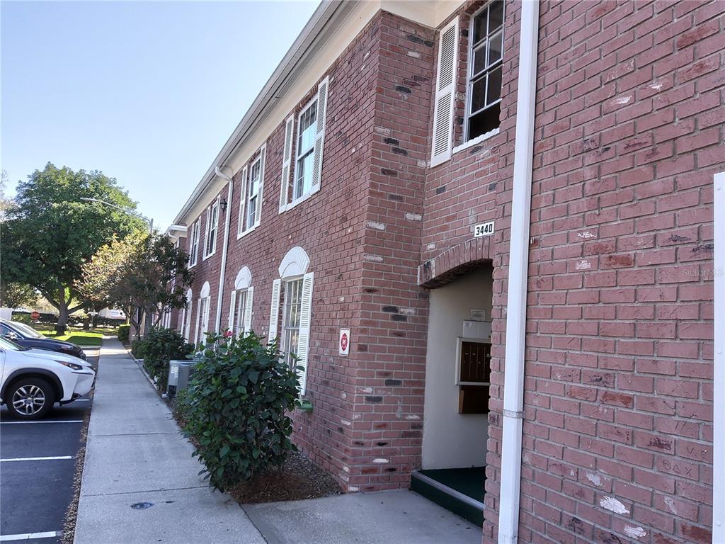 A multi-story brick apartment building features white shutters, a sidewalk, and a recessed entryway — 3440 41ST AVE SOUTH UNIT 187, ST PETERSBURG, FL